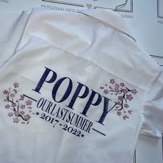 a white shirt with the words poppy on it is sitting on top of some papers