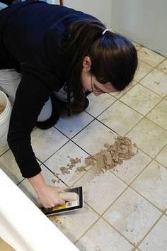 a woman kneeling down on the floor in front of a toilet with dirt all over it