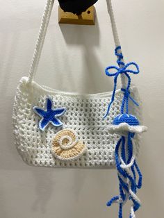 a crocheted purse hanging from a hook on a wall with blue and white trim