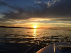 the sun is setting over the water as seen from a boat