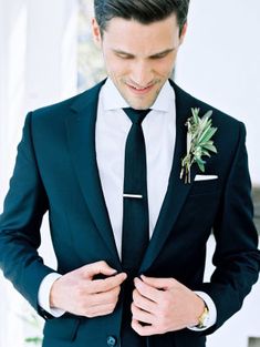 a man wearing a suit and tie with a boutonniere on his lapel