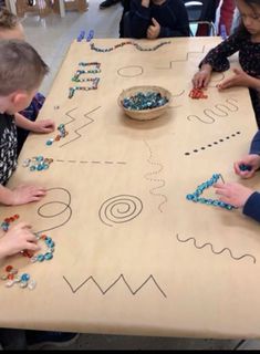 children are playing with beads on a table