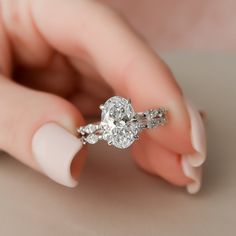 a woman's hand holding a diamond ring on top of her finger with the other hand