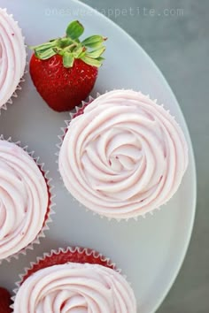 cupcakes with frosting and strawberries on a plate