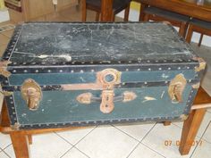 an old trunk sitting on top of a wooden table next to a dining room table