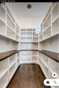 an empty walk in closet with white shelving and wood flooring, along with hard wood floors