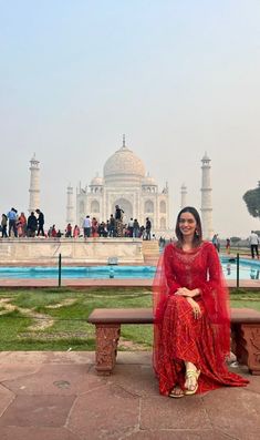 a woman sitting on a bench in front of the taj - izzar