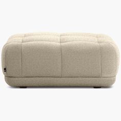 an upholstered, beige ottoman with black legs and foot rests on a white background