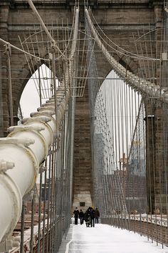 people walking across the brooklyn bridge on a snow covered day in new york city, ny