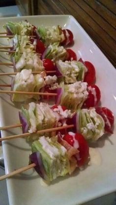 several small skewers filled with lettuce and tomatoes on a white plate