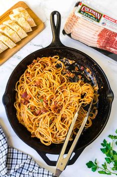 a skillet filled with spaghetti and bacon