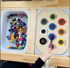 the child is playing with his toys in the wooden trays on the table,