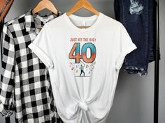 a white shirt with the number forty on it hanging next to some jeans and plaid shirts