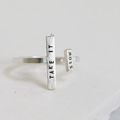 One of our favorite gift-able rings, the Double Adjustable Ring is an eye-catching way to inspire & encourage. An adjustable, asymmetric ring with a tiny phrase of inspiration. Letters are individually stamped by hand, making each ring one of a kind. The message is centered on each bar in our signature teeny-tiny uppercase block font. For an unconventional look, try stacking with our diamond dusted adjustable rings. details+ longer bar measures 5/8" wide x 2 mm tall+ shorter bar measures 1/4" wi Adjustable Meaningful Rings As Gift, Meaningful Adjustable Rings As Gift, Modern Adjustable Midi Rings For Promise, Adjustable Open Ring With Meaningful Style, Adjustable Inspirational Sterling Silver Rings, Inspirational Adjustable Sterling Silver Rings, Inspirational Adjustable Ring, Adjustable Sterling Silver Stackable Rings, Unique Adjustable Midi Rings For Everyday