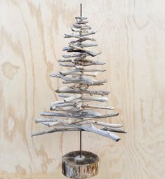 a small tree made out of driftwood in front of a wooden wall