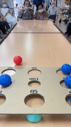 a table with several balls on it and people sitting in the background looking at them