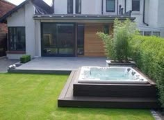 a large hot tub sitting in the middle of a lush green yard next to a house