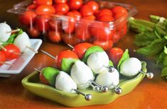 small trays filled with tomatoes and mozzarella on skewers next to fresh basil