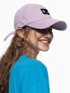 a girl with long hair wearing a purple hat and blue shirt smiling at the camera