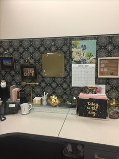 an office desk with a calendar, phone and other items on the wall behind it