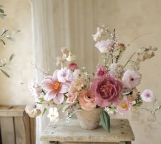 a vase filled with lots of flowers on top of a table