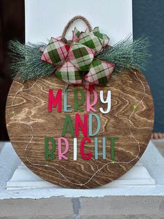 a merry and bright wooden sign with plaid bows on it's front door hanger