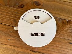 a free bathroom sign hanging on a wooden wall