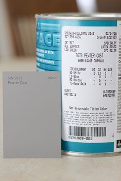 a can of white paint next to a piece of gray paper on a counter top