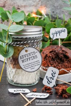 an image of some food in a jar with stickers on the side and green leaves around it