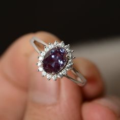 a close up of a person holding a ring with a purple stone