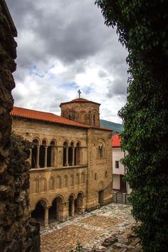 an old stone building with a steeple on the top and red tiled roof is seen through a window