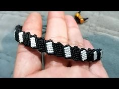 a hand holding a black and white beaded bracelet