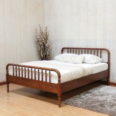 a bed sitting on top of a hard wood floor next to a wall with white walls