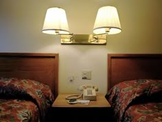 two twin beds in a hotel room with lamps on the nightstand and telephone to the side