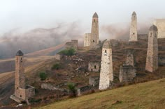 an old castle sits on top of a hill in the foggy mountains above it