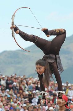 a woman is performing an aerial acrobatic trick in front of a crowd