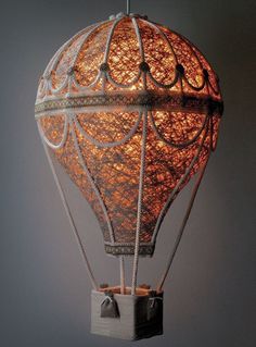 a lit up hot air balloon hanging from a ceiling fixture in the shape of a cage