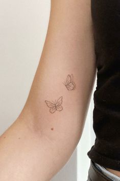 two small butterflies on the arm by a woman's left arm, one is black and white