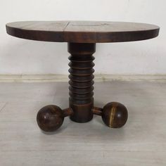 a round wooden table with two metal balls on the base and one is turned upside down