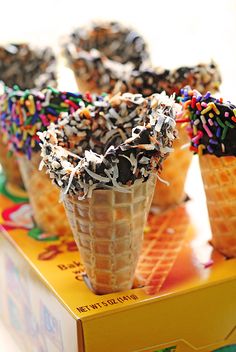 four ice cream cones with sprinkles and chocolate on top are sitting on a yellow tray