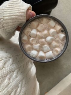 someone holding a cup of hot chocolate with marshmallows