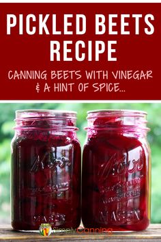 two jars filled with pickled beets sitting on top of a wooden table