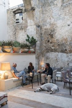 people are sitting at tables in an outdoor patio with plants and potted plants on the wall