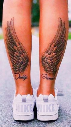 a woman's legs with tattoos and wings on her leg, both showing the word daddy