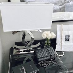 a black table topped with a white flower and a purse next to a framed photo