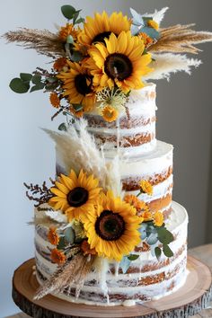 a three tiered cake with sunflowers and feathers