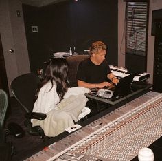 two people sitting in front of a mixing desk