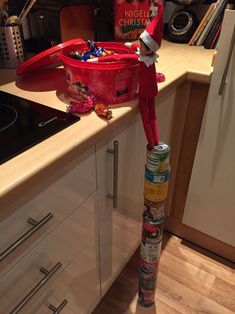 an elf standing on top of a can in the middle of a kitchen with candy