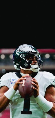 a close up of a football player holding a ball in his hands and wearing a helmet