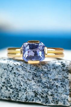 a tan and yellow gold ring with an amethorate stone in the middle